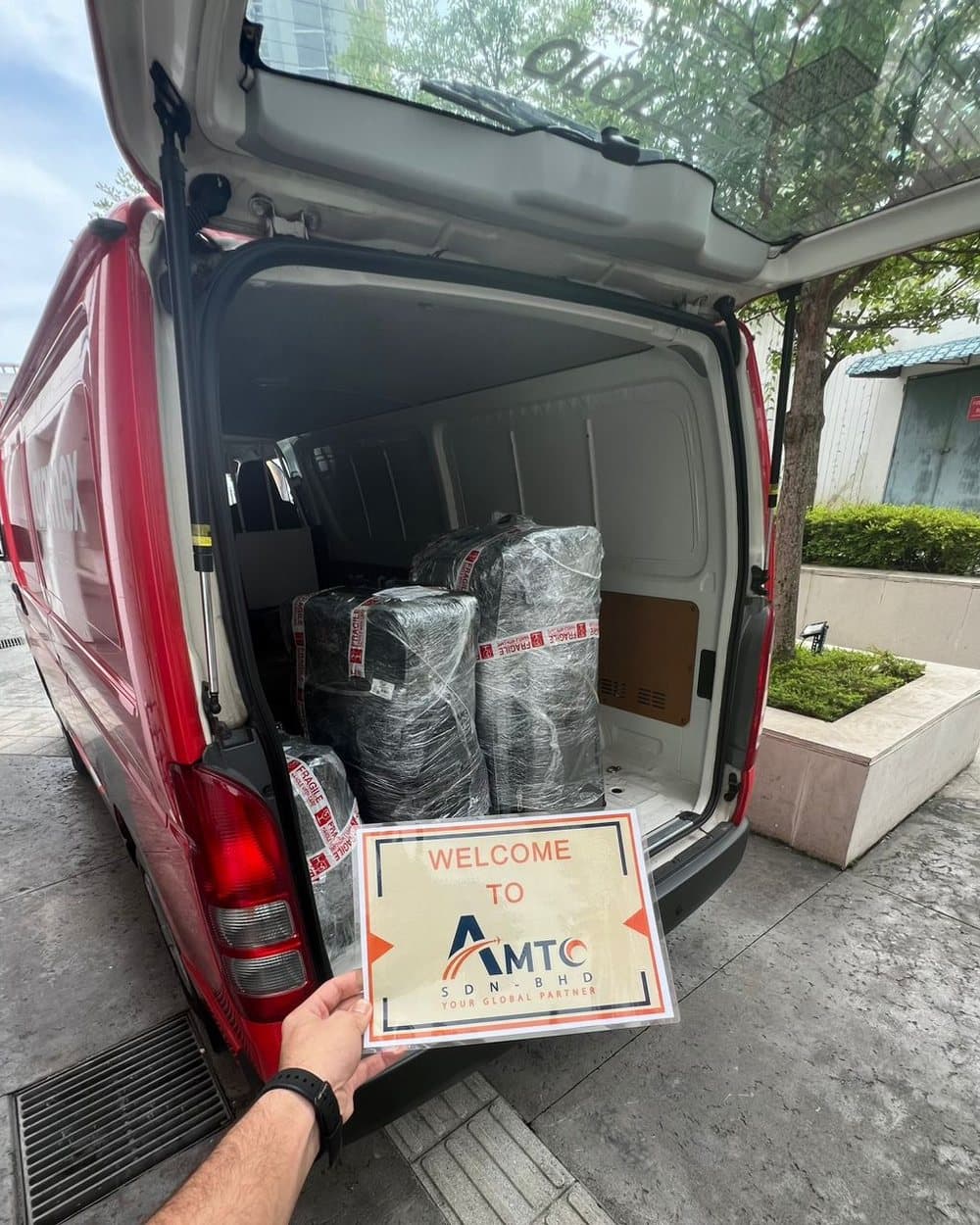 Wrapped suitcases in an Aramex van, with an AMTC welcome sign